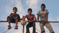 Drei Kinder in Honduras sitzen auf einem Zaun